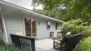 A wooden deck leading to a house with a sliding glass door, a small table, and two chairs.