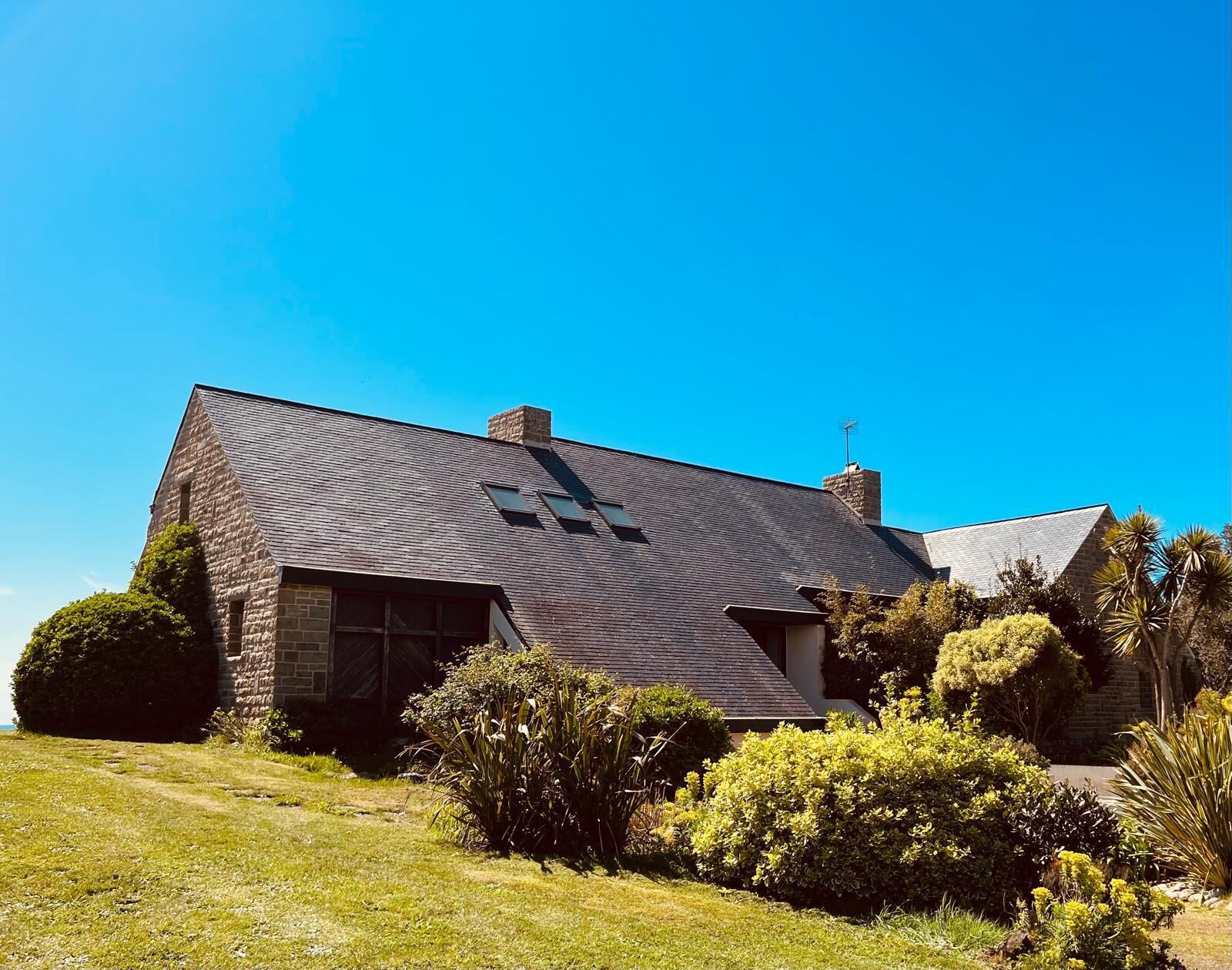 A house with a sloped roof, stone exterior, and a well-maintained garden.