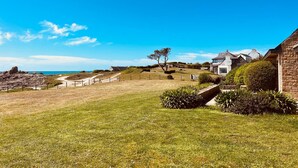 Une propriété située sur la côte, dotée d’une pelouse bien entretenue, d’un bâtiment en pierre et offrant une vue sur la mer.