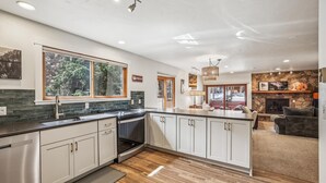 Una cocina moderna con un ventanal grande, una chimenea de piedra y una zona de estar acogedora.