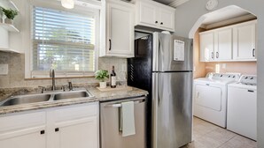 A modern kitchen with white cabinets, stainless steel appliances, a built-in dishwasher, and a window with blinds. - Charming 2BR Retreat | Pet Friendly! (Colorado Springs)