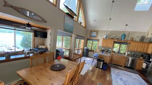 Une cuisine spacieuse avec des meubles en bois, un coin repas comprenant une table et des chaises en bois, et de grandes fenêtres offrant une vue sur l’extérieur.
