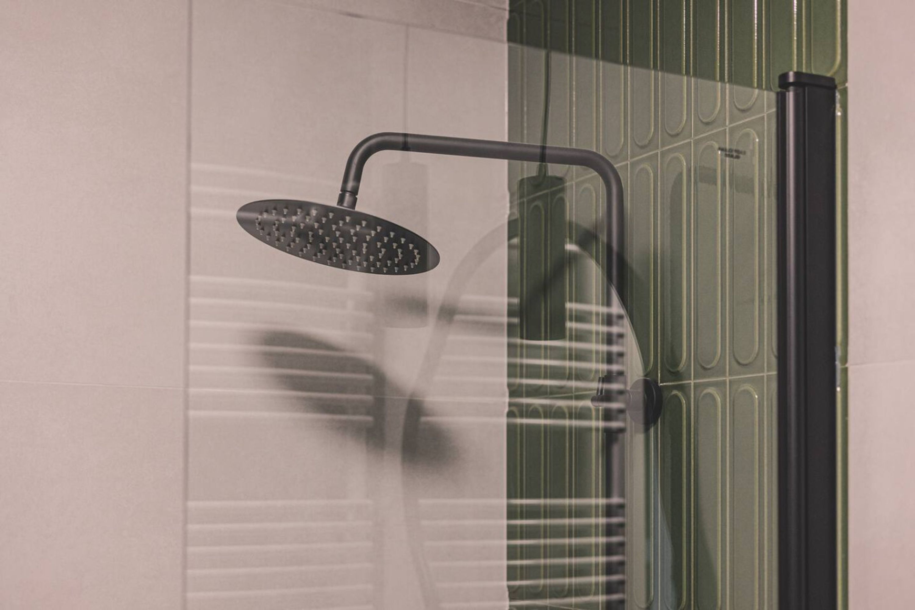 A shower with a curved head and a wall-mounted control panel.