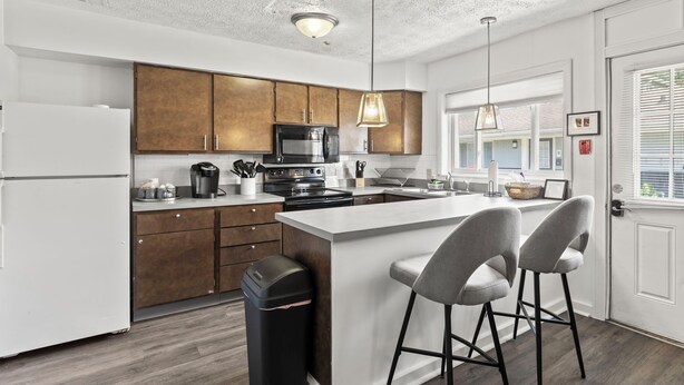 A modern kitchen with wooden cabinets, a central island, and bar stools. - Spacious 1-Bedroom Apartment in the Heart of Indy (Indianapolis)