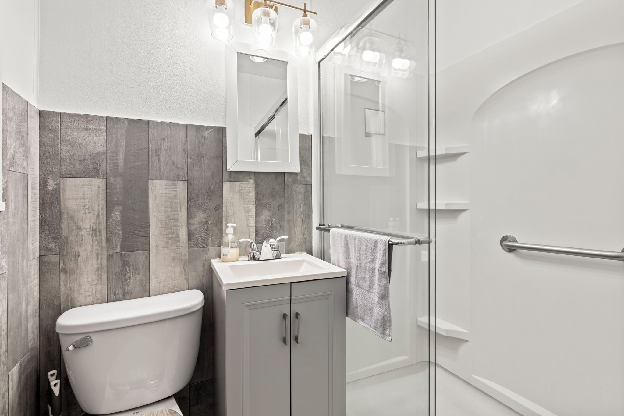 A modern bathroom with a toilet, sink, and glass shower enclosure.
