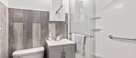 A modern bathroom with a toilet, sink, and glass shower enclosure.