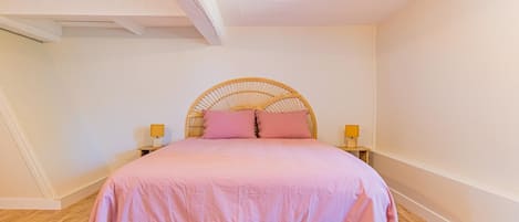 A bedroom with a bed, two bedside lamps, and a wooden floor.