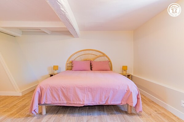 A bedroom with a bed, two bedside lamps, and a wooden floor. - Chez Jean - BOIS SAINTE MARIE (BOIS SAINTE MARIE)