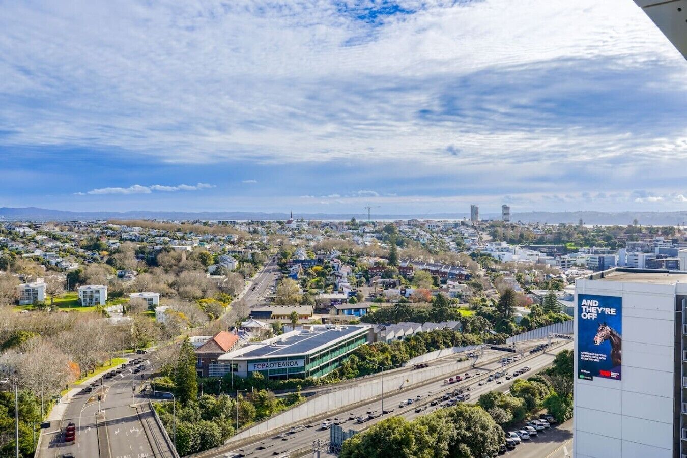 Vista aérea de una zona residencial con casas, una calle y un edificio grande con un letrero.