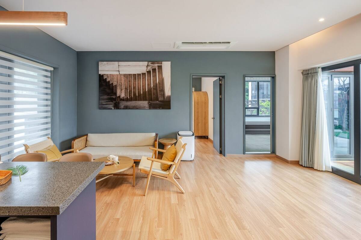A modern living room with a sofa, chairs, a coffee table, and a dining area with a counter.