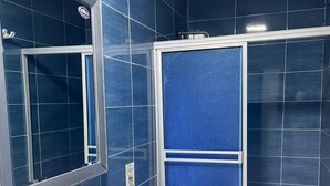 A bathroom with dark blue tiles, a white sink, a toilet, and a shower enclosure. - Apartment 202A (San Andrés Islas)