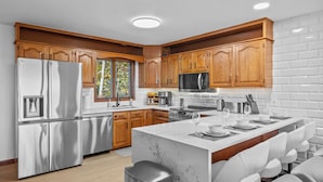 A modern kitchen with wooden cabinets, stainless steel appliances, and a marble island.