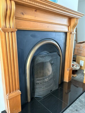 A fireplace with a wooden mantel and a metal screen door.
