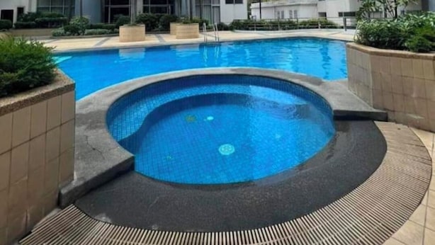 A modern residential building with a central swimming pool surrounded by palm trees and a clear sky. - One Palm Tree Villas near NAIA 3 (Pasay)
