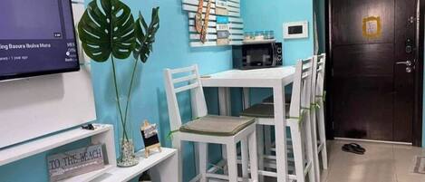 Una habitación con pared azul, muebles blancos, un televisor y una puerta con cerradura.