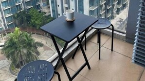 A balcony with a table and chairs, overlooking a residential area with modern buildings. - One Palm Tree Villas near NAIA 3 (Pasay)