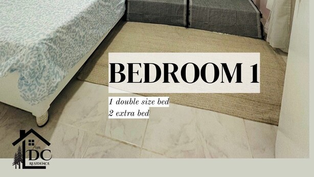 Een slaapkamer met een tweepersoonsbed, twee extra bedden en een sofa met decoratieve kussens.