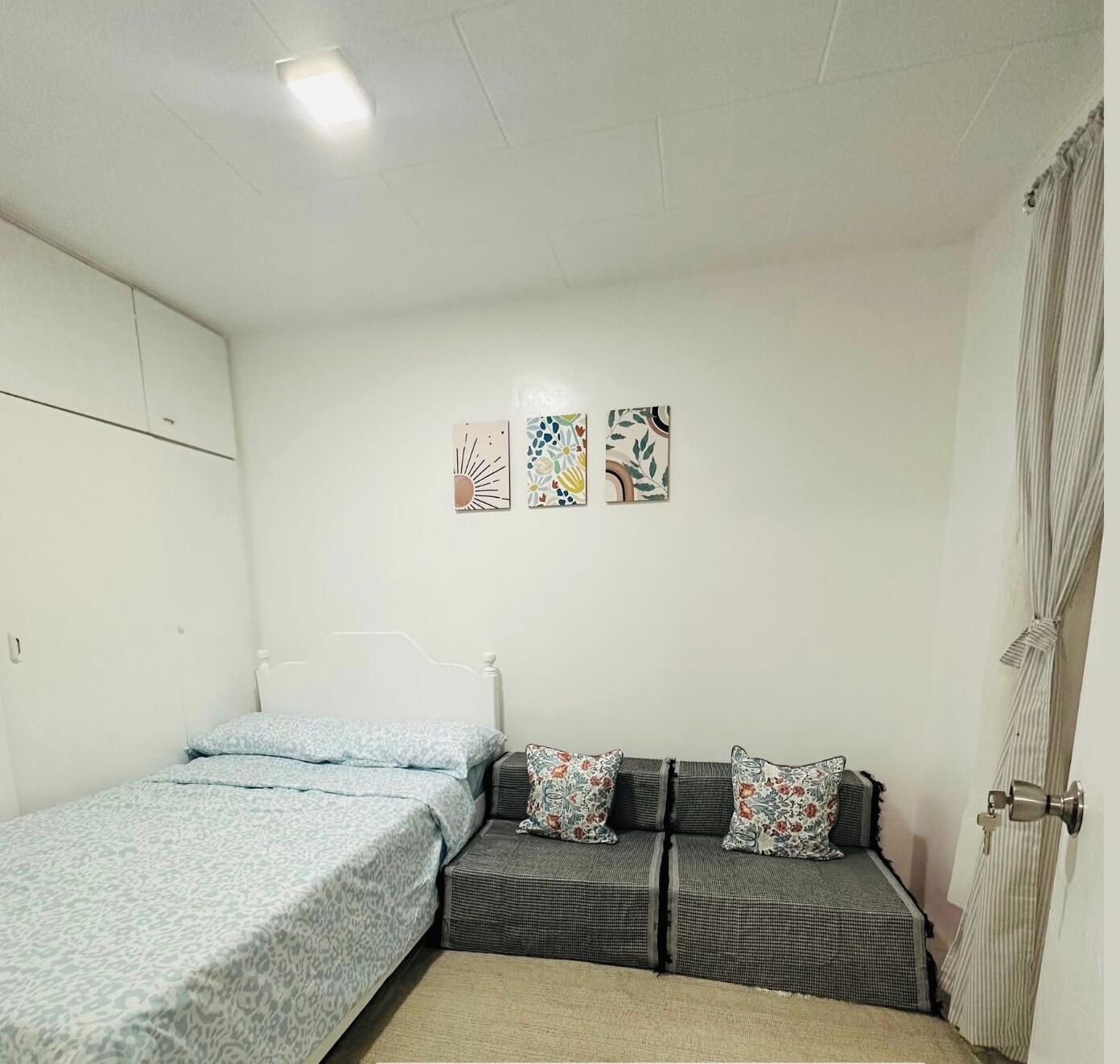 Ein Schlafzimmer mit einem Doppelbett, zwei zusätzlichen Betten und einer Couch mit dekorativen Kissen.
