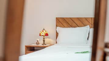 A neatly made bed with white linens, a wooden headboard, and a bedside table with a decorative lamp.