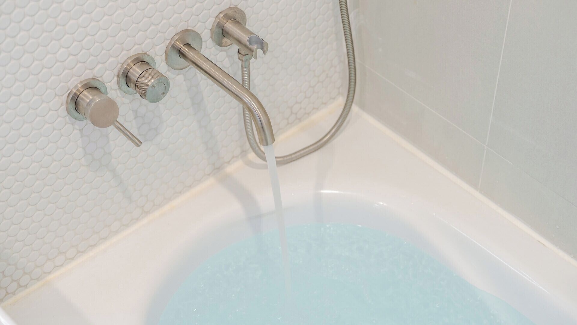 Una bañera con ducha y mandos.