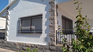 A building with white exterior walls and stone accents, featuring barred windows and a stone pillar.