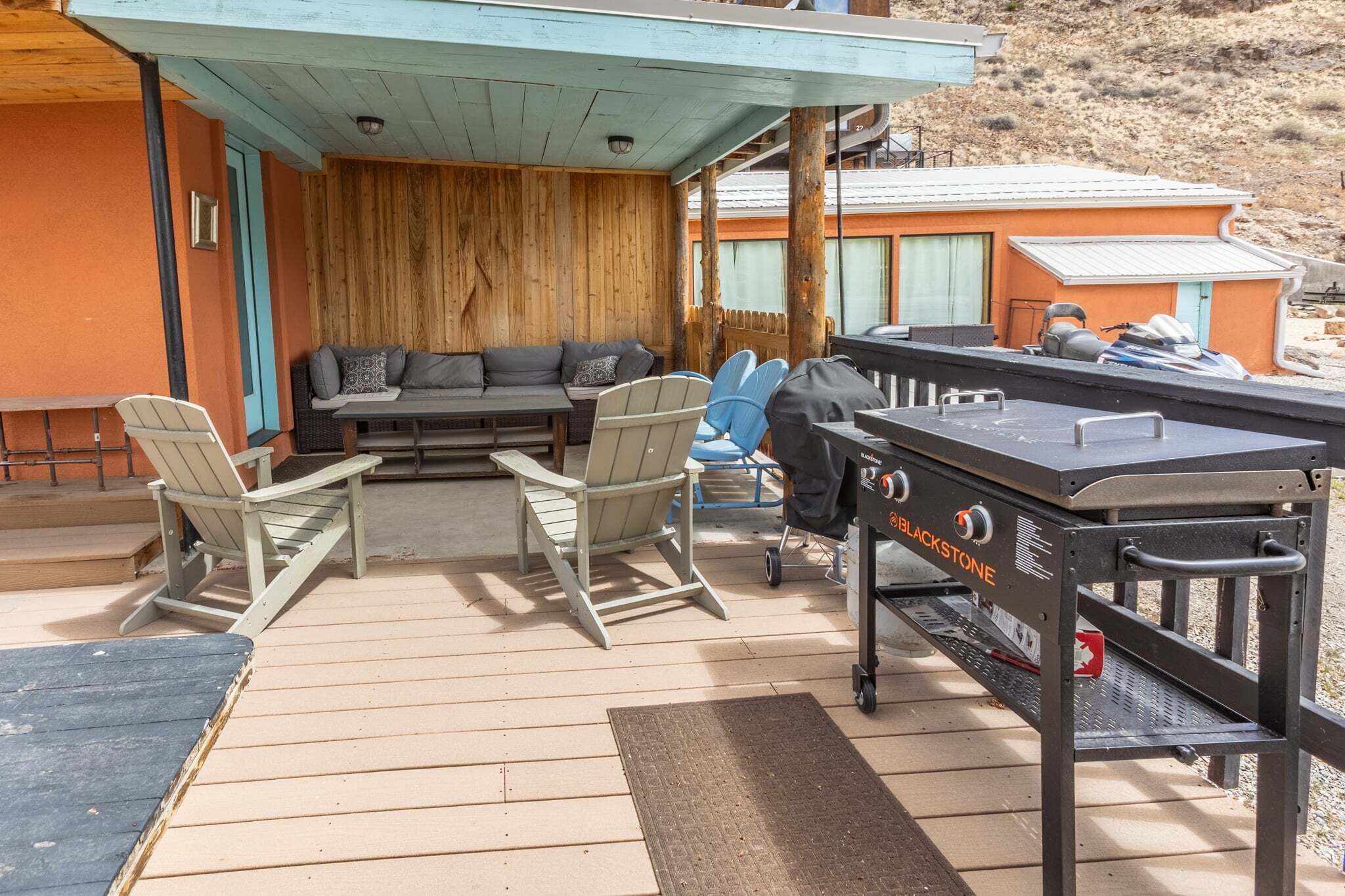 An outdoor deck with a grill, seating area, and chairs.