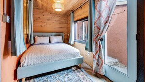 Una habitación con paneles de madera, una cama, una ventana y cortinas.