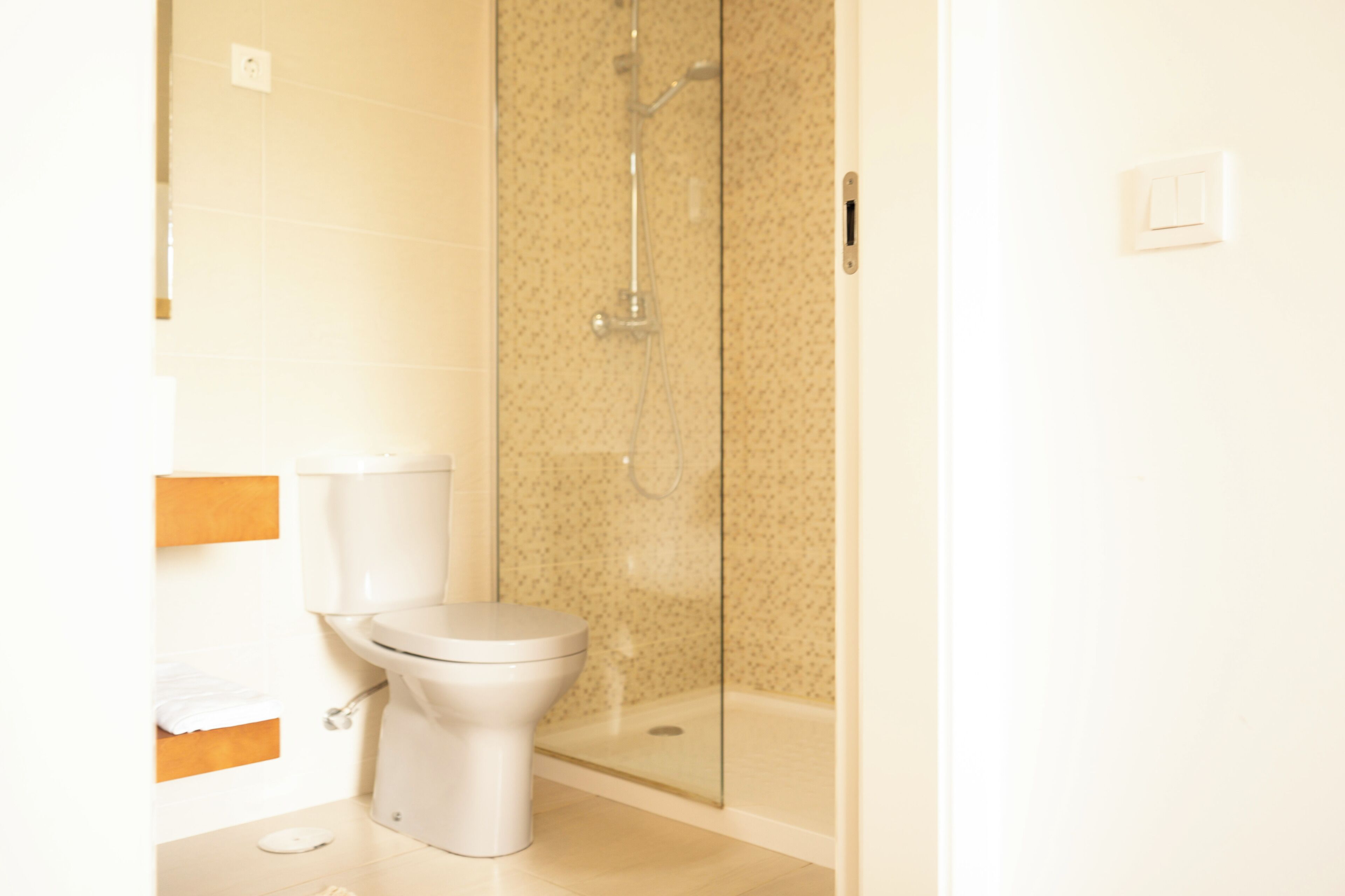 Un bagno con il water, uno spazio doccia e un interruttore luce a parete.
