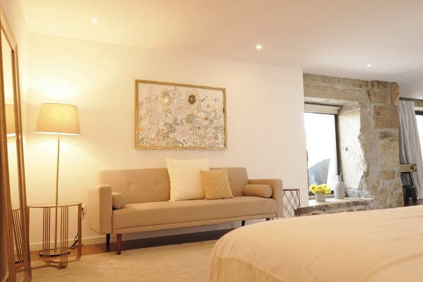 A room with a sofa, a lamp, a painting, and a stone wall. - CasadAmares (Amares)
