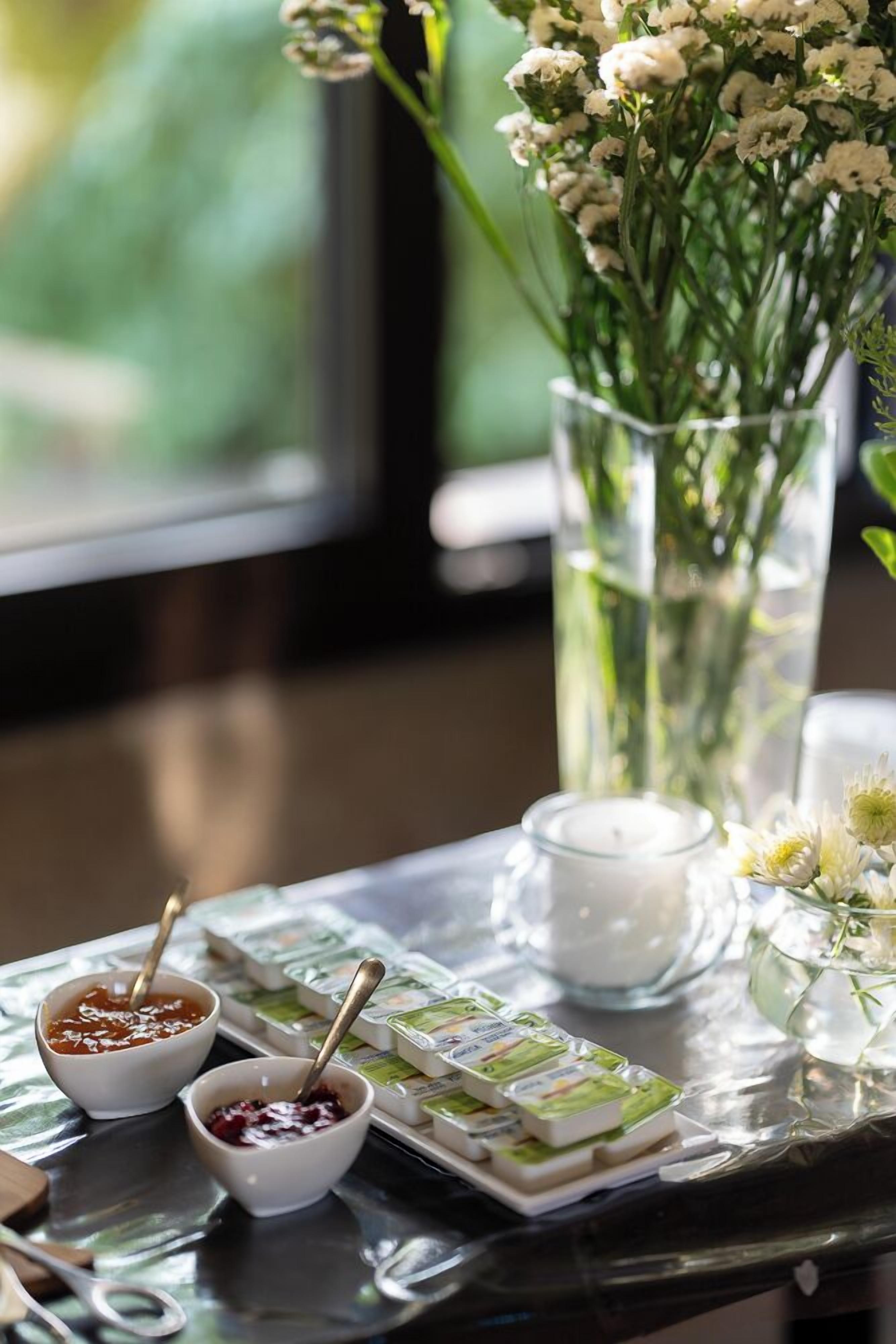 Una mesa con frascos de salsas, una vela y un florero con flores.