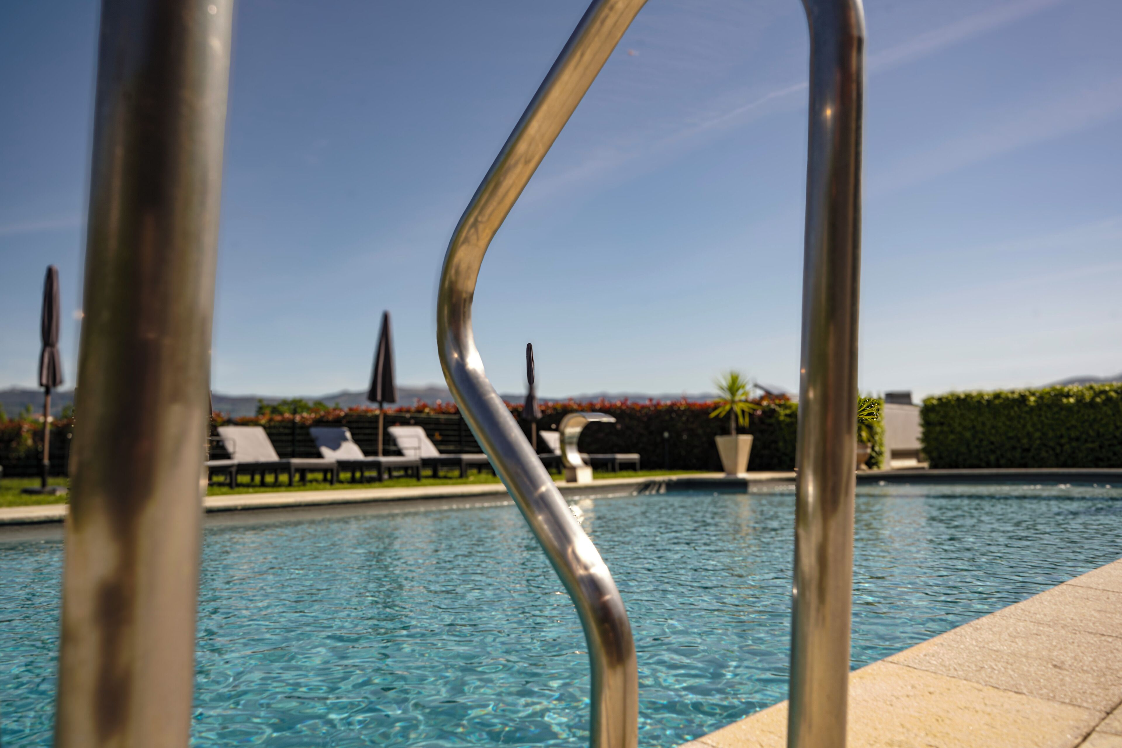 A swimming pool with lounge chairs and metal railings.