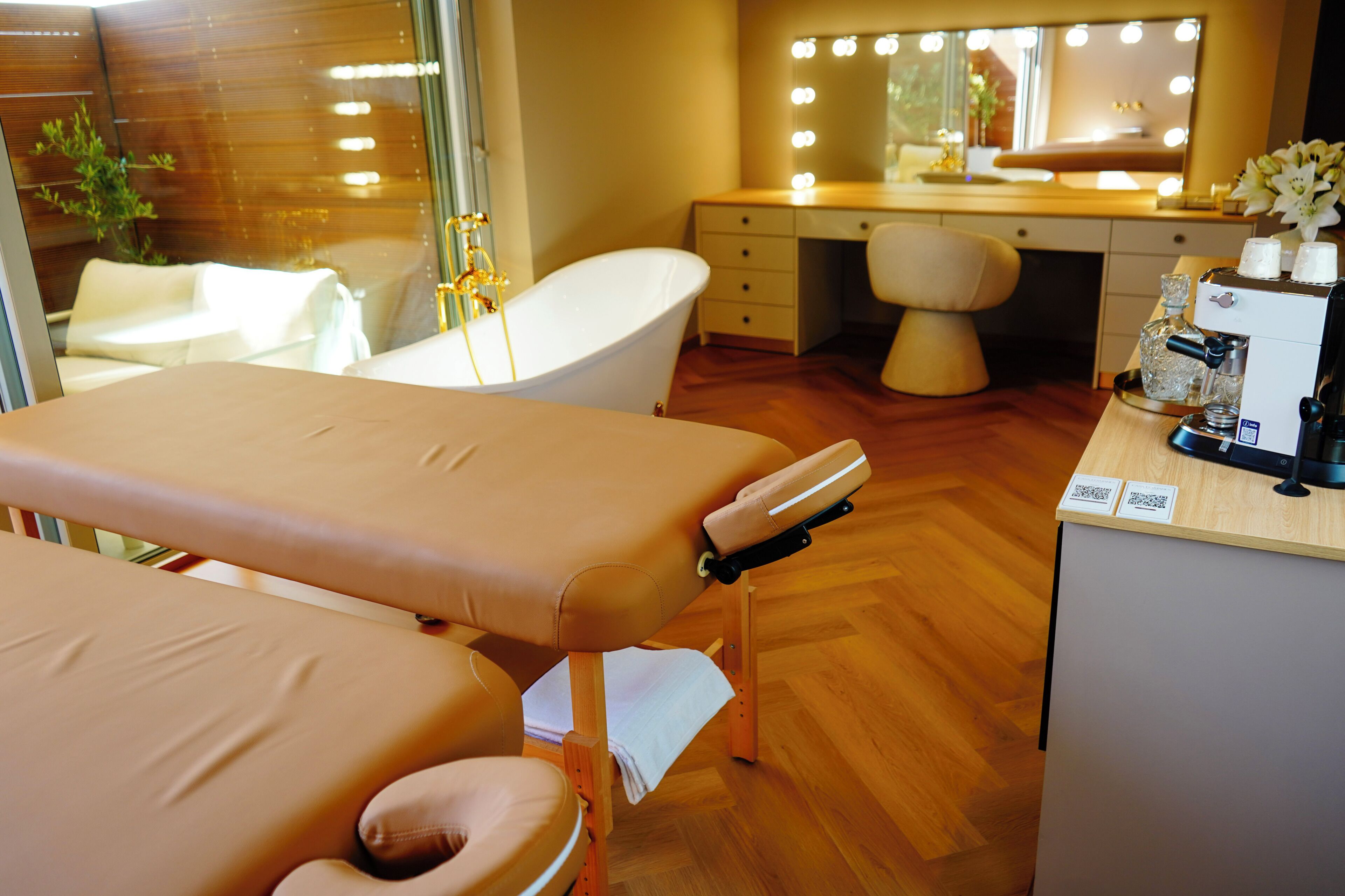 A room with a vanity, a bathtub, and a massage table.