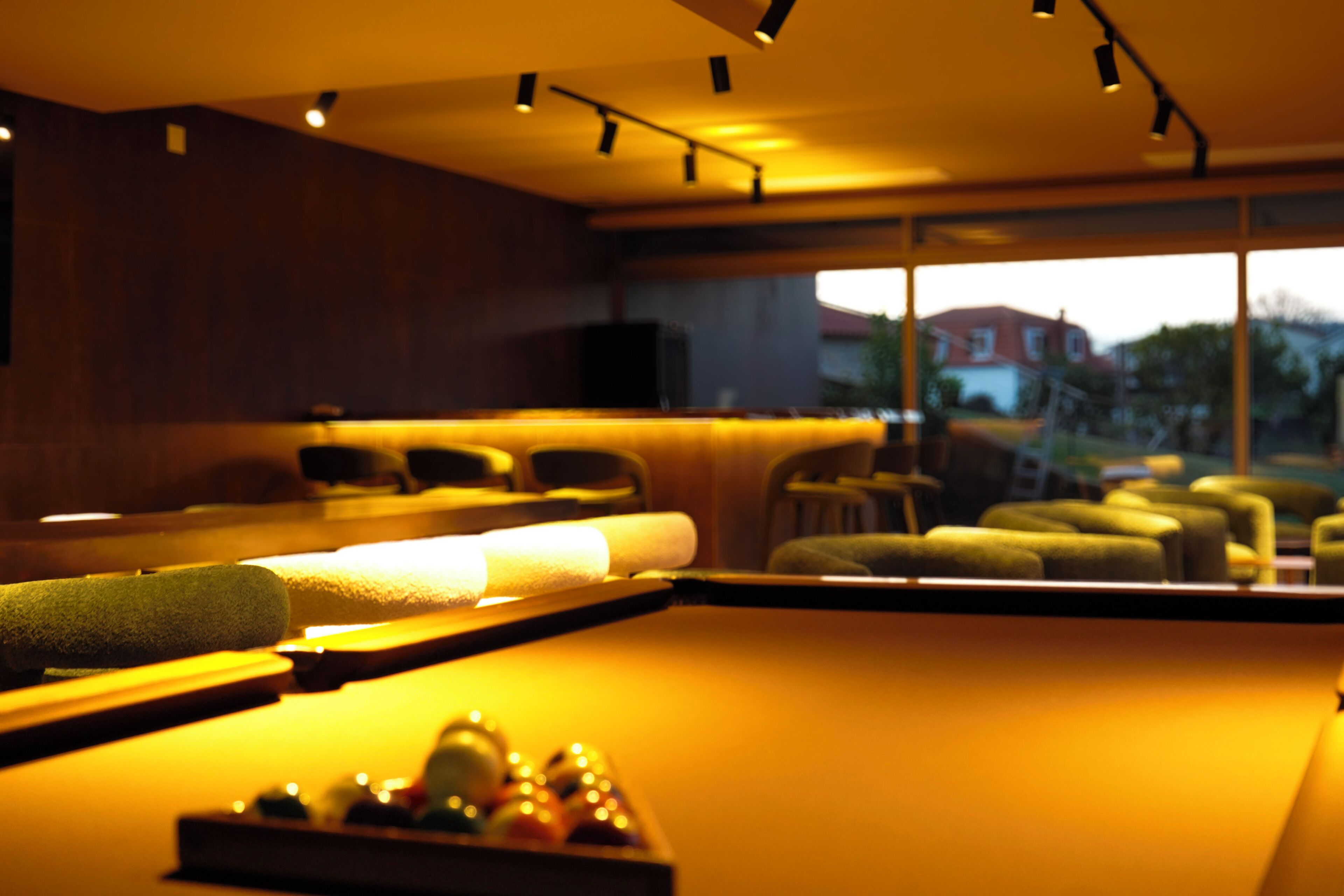 A modern spa room with a massage table, chairs, and a view of the outside.