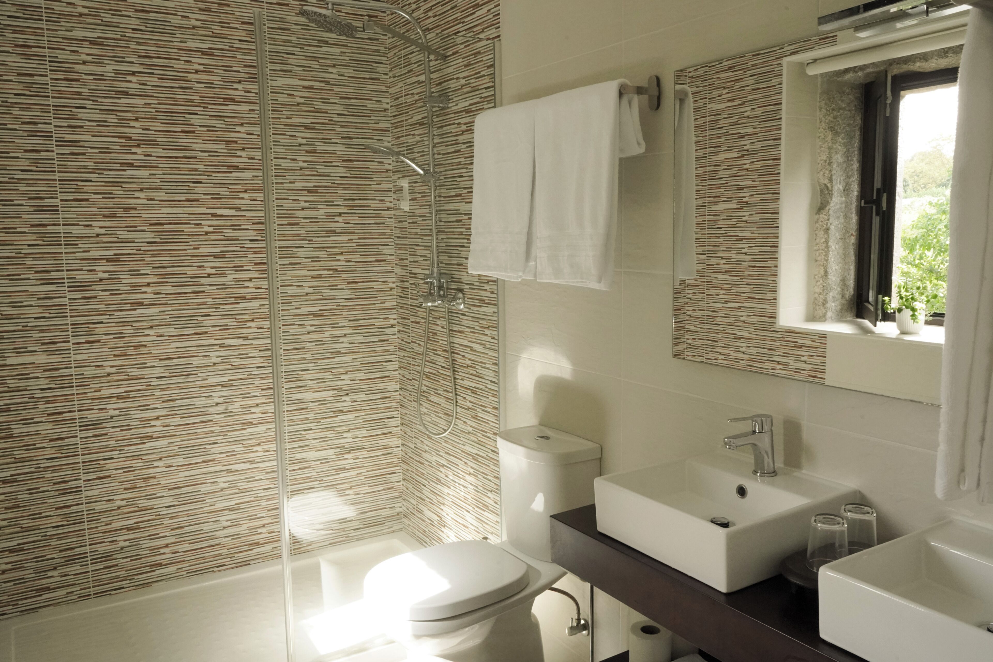 A modern bathroom with a shower, toilet, and two sinks.