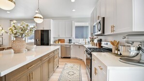 A modern kitchen with white cabinets, stainless steel appliances, and a central island. - Modern 6br near skiing, luxe, sleeps 12, hot tub (Heber City)