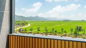 A view of a green field with a road and trees, seen through a window with a wooden frame. - Suncheon The Sky Pool Villa (Suncheon)