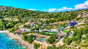 Un complejo turístico frente al mar con varias villas, paneles solares y una playa.