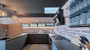 Una cocina moderna con pared de ladrillo, horno empotrado y vitrina de copas de vino.