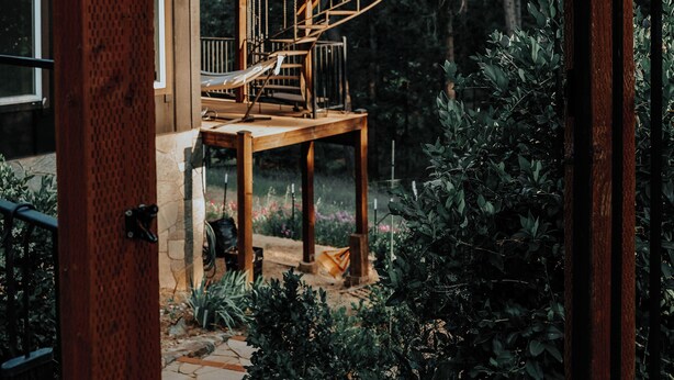 A two-story wooden house with a spiral staircase leading to a balcony.