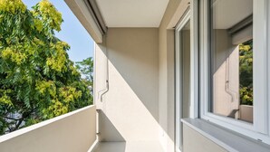 Varanda com vista desobstruída para uma árvore e fachada de um prédio.