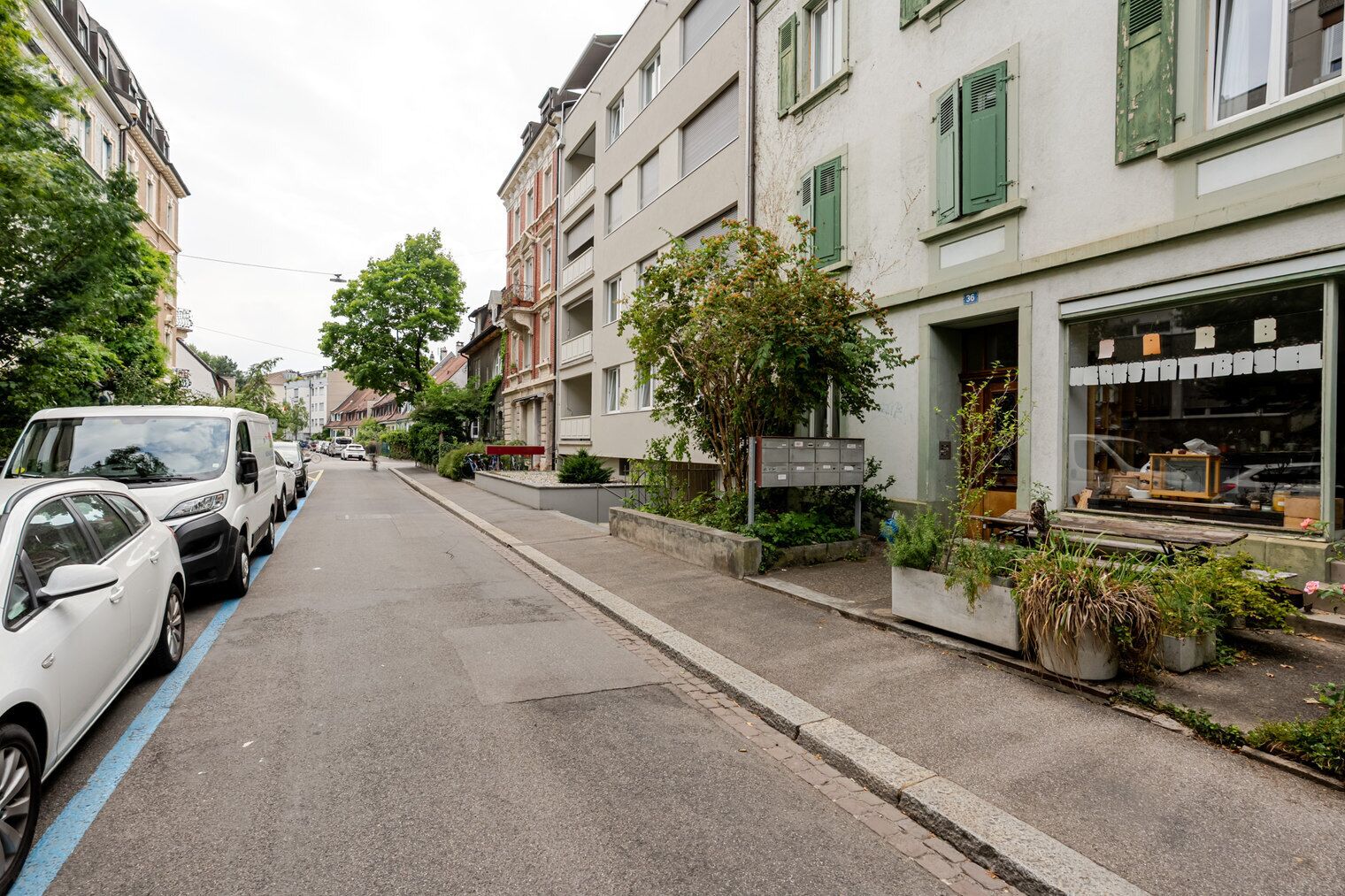 A street with parked cars and buildings with green shutters.