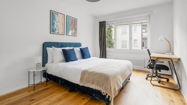 Quarto com cama, escrivaninha e janela.