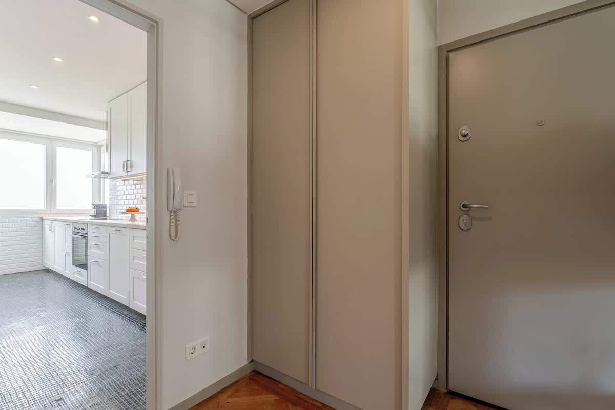 A modern kitchen with white cabinets, a tiled backsplash, and a wooden floor.