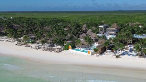 A beach resort with thatched-roof buildings, a swimming pool, and palm trees. - Orange Beach House 10bdr in Tulum Hotel Zone, Wake up every morning on the beach (Tulum)