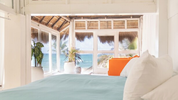 A bedroom with a bed, a window with a view of the ocean, and a potted plant. - Orange Beach House 10bdr in Tulum Hotel Zone, Wake up every morning on the beach (Tulum)