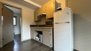 A compact kitchen with a refrigerator, microwave, and cabinets. - Saddle Mountain Lodge (Blue River)