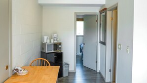 A narrow hallway with a wooden dining table and chairs, a microwave, and a refrigerator. - Saddle Mountain Lodge (Blue River)
