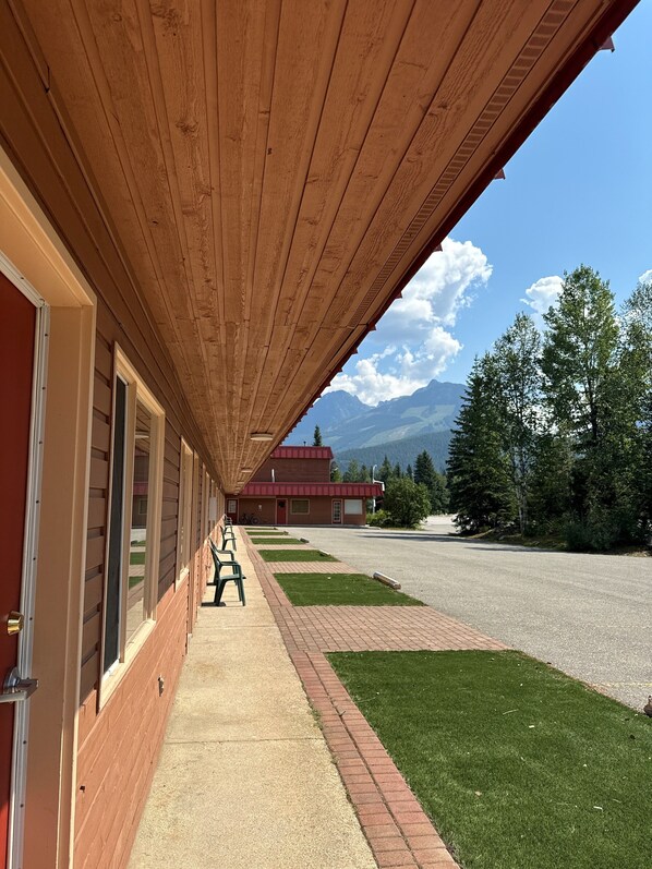 A covered walkway with wooden beams, leading to a building with a red roof. - Saddle Mountain Lodge (Blue River)