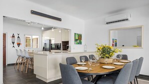 A modern kitchen with a central island, dining area with grey chairs, and a large mirror. - 5BR @ Top of The Hill  Views Surrounded by Nature (Santa Cruz)