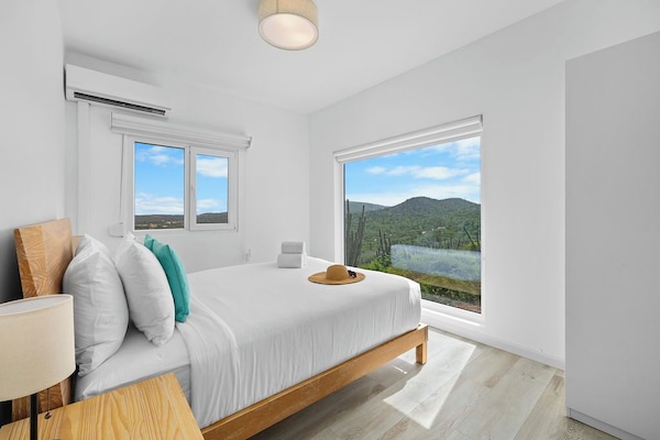 Enjoy ultimate relaxation in this bedroom featuring a comfortable bed, refreshing AC, a TV for your favorite shows, and a picturesque outside view right from your window.